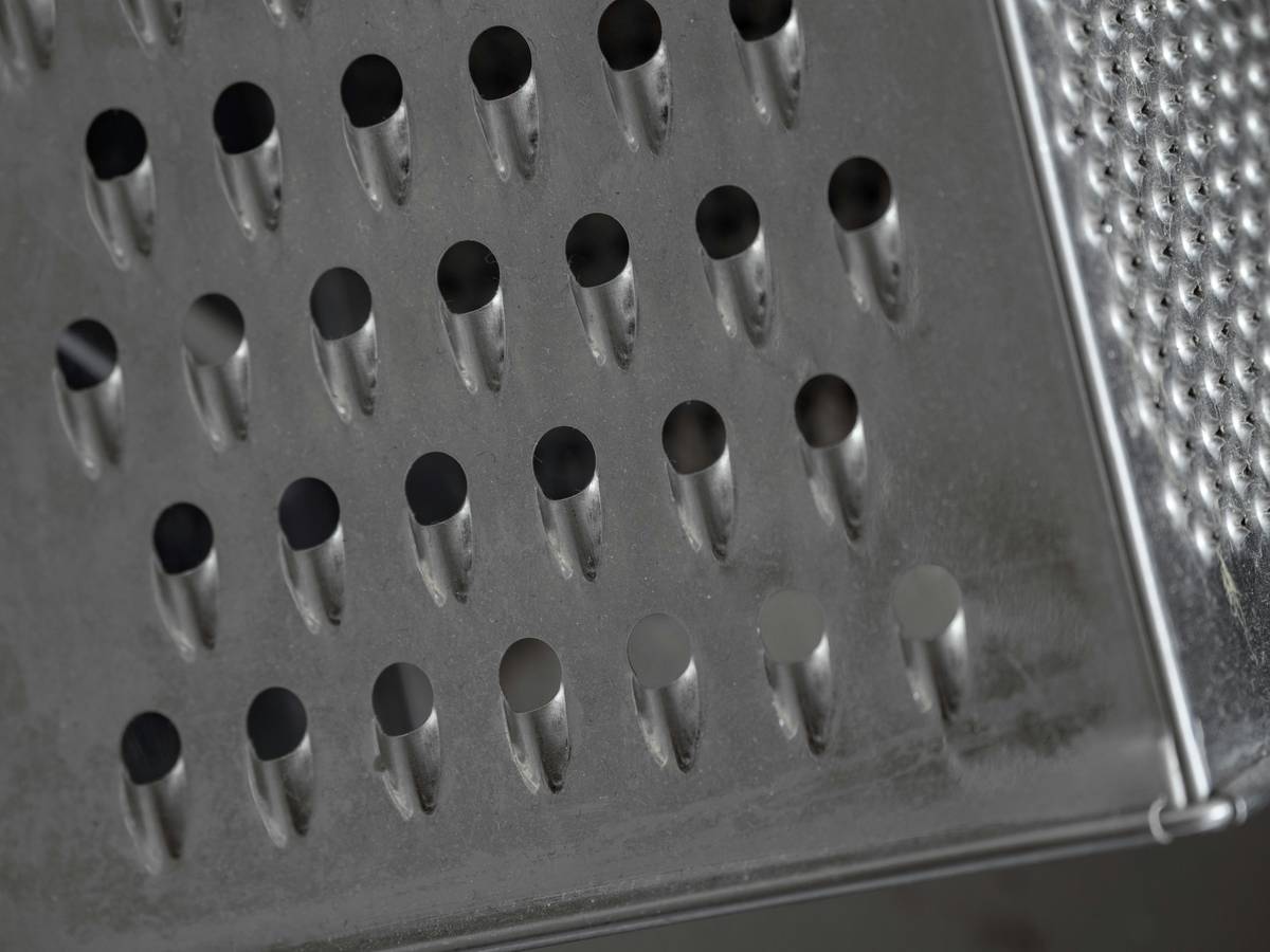 food processor with cheese grater attachment shredding Parmesan cheese into fine, even flakes