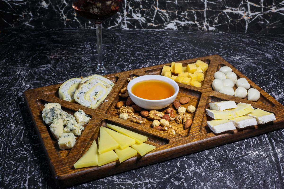 cheese serving board with box grater, grated parmesan pile, and small knife on rustic wood surface